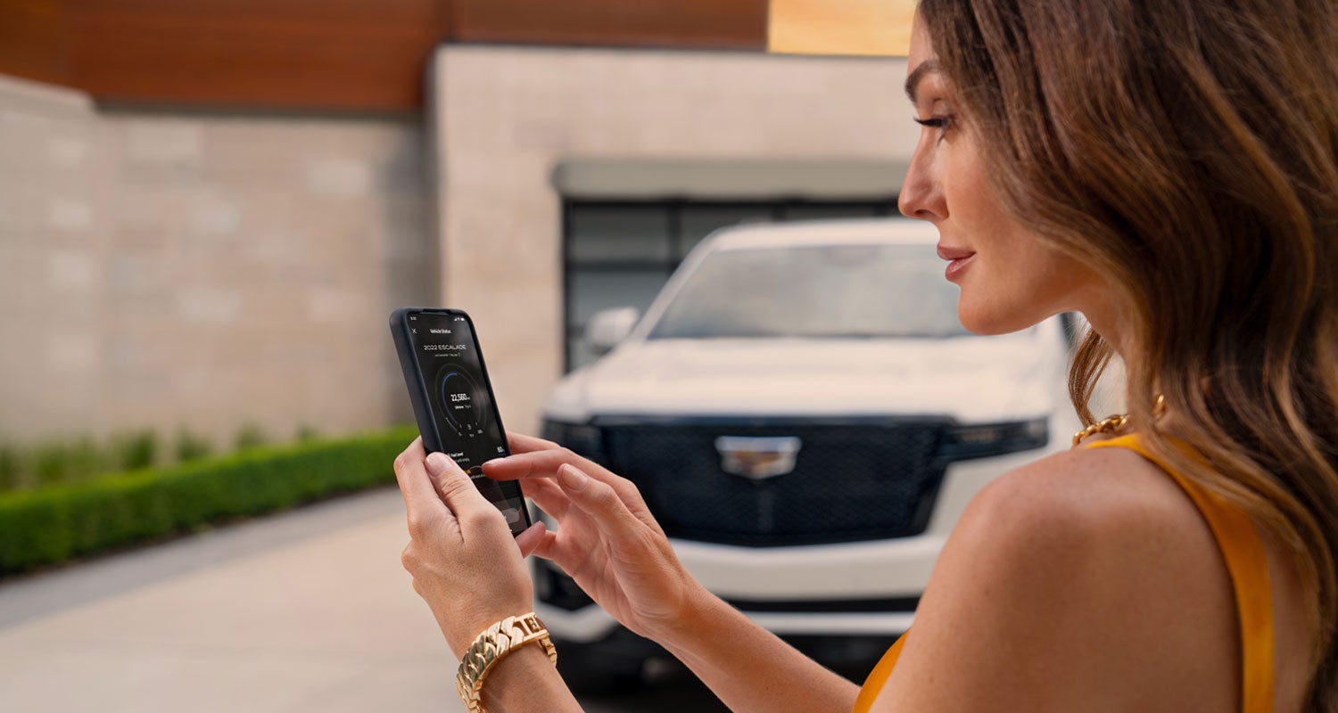 lady checking her mobile with a Cadillac vehicle background | Faulkner Cadillac Mechanicsburg in mechanicsburg PA